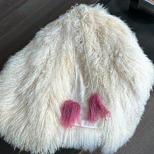 Sheep fur cape with fuchsia pom pom.
